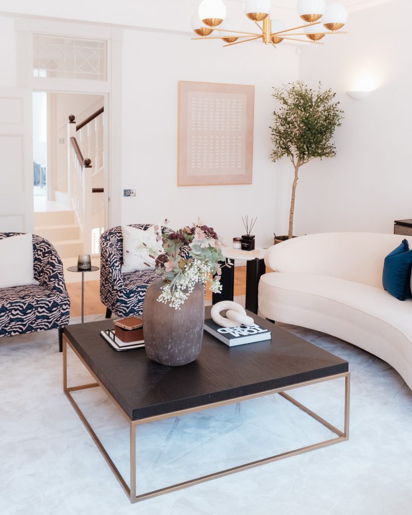 OB Private luxury property living room photography by 36 Studios — curved cream sofa, animal print armchair and brass chandelier